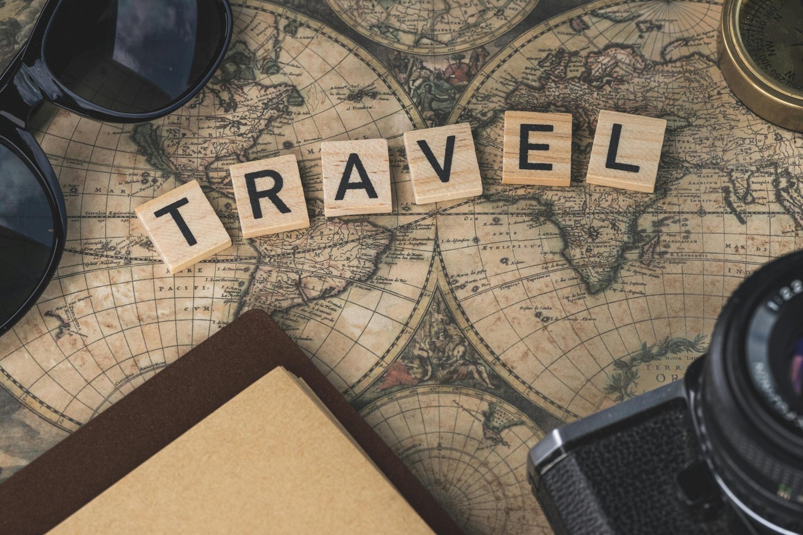 Vintage map with travel essentials like camera and sunglasses arranged in a flat lay, perfect for adventure themes.